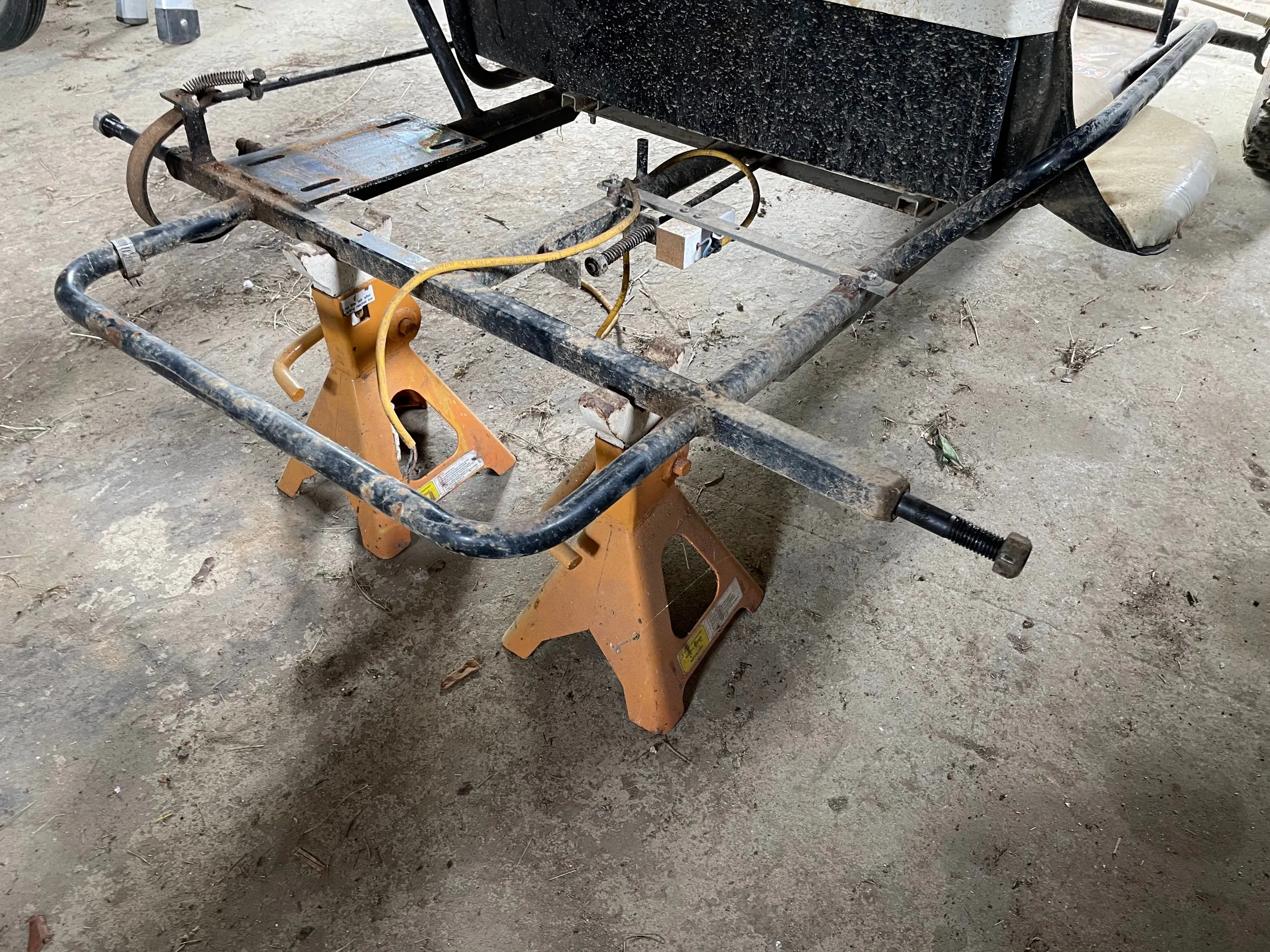 The bare rear section of the frame on jack stands with the axle removed