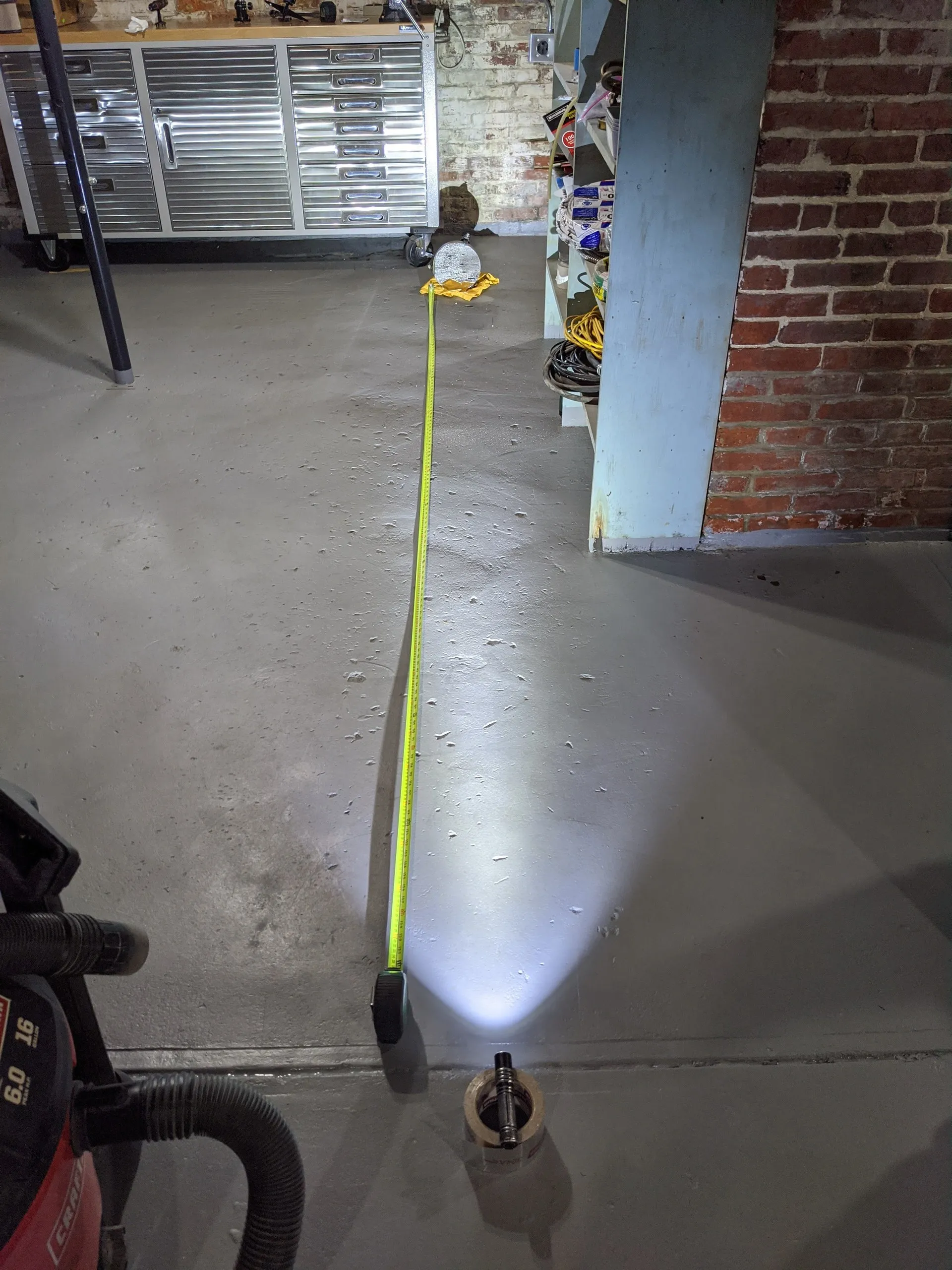 A flashlight aimed into the primary mirror, its reflected spot of light measured against a tape measure to confirm the focal length