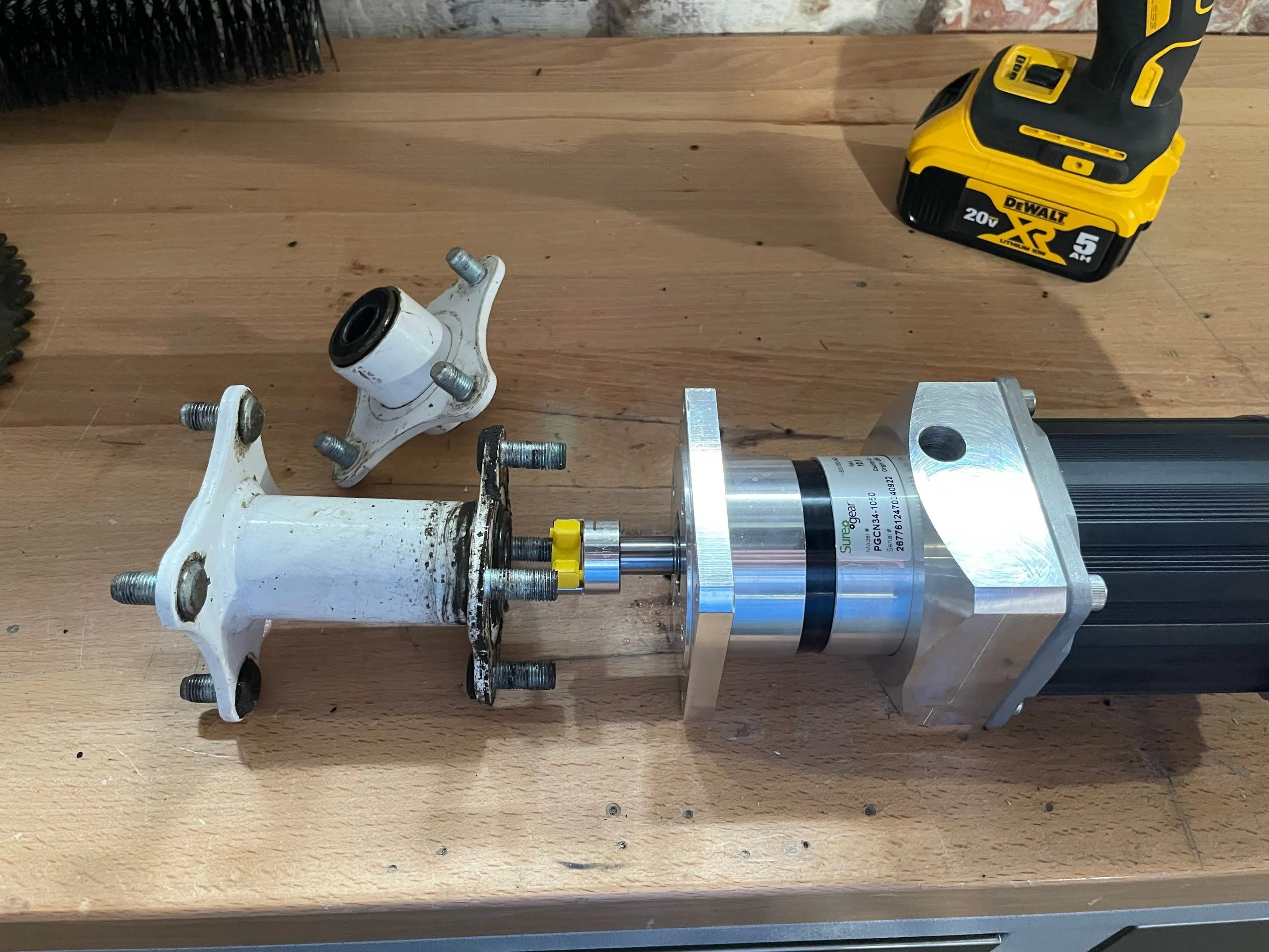 A motor and gearbox on a workbench with a wheel hub and shaft loosely assembled against the gearbox output flange