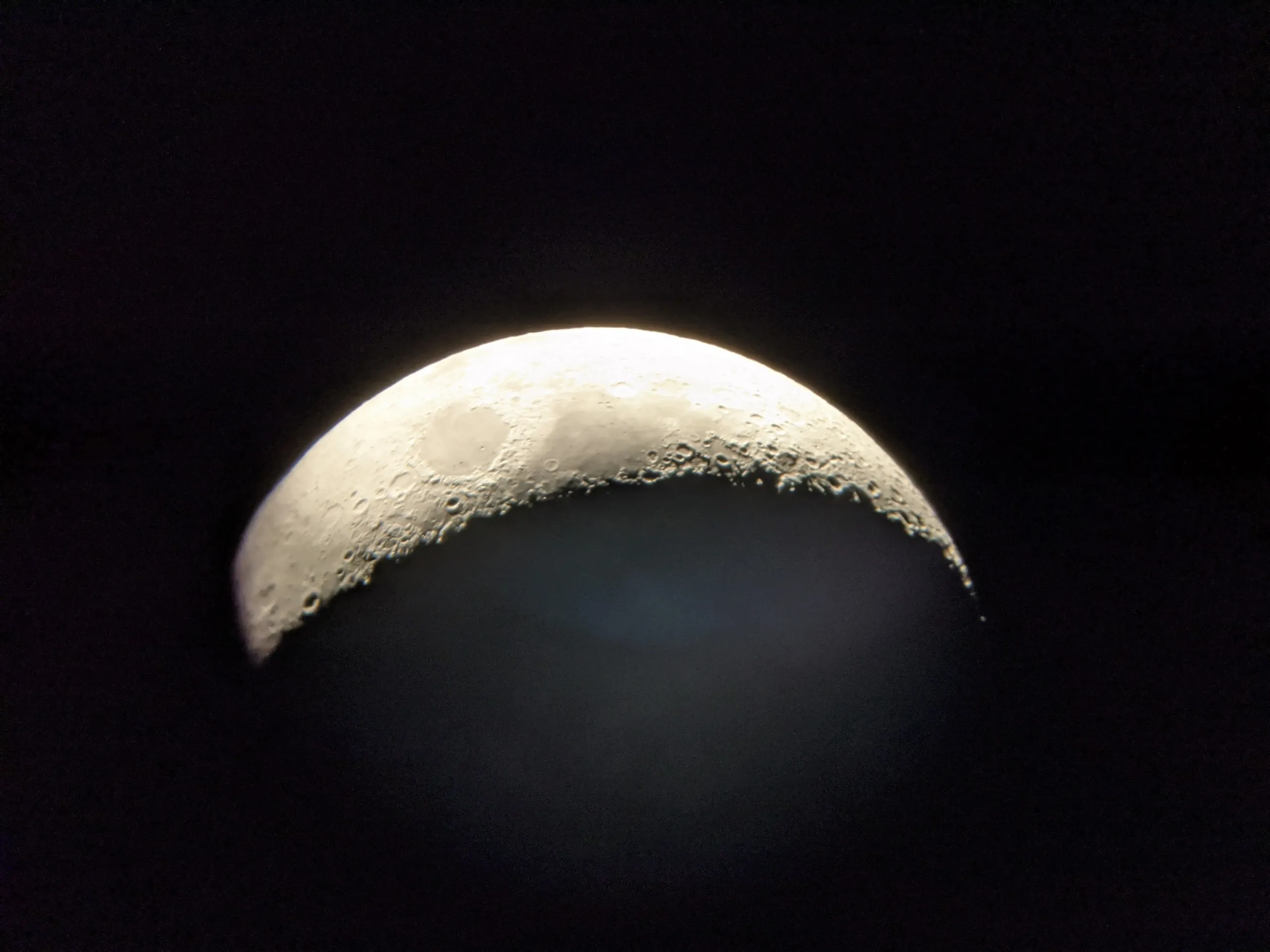The moon through the eyepiece, showing crater detail along the terminator