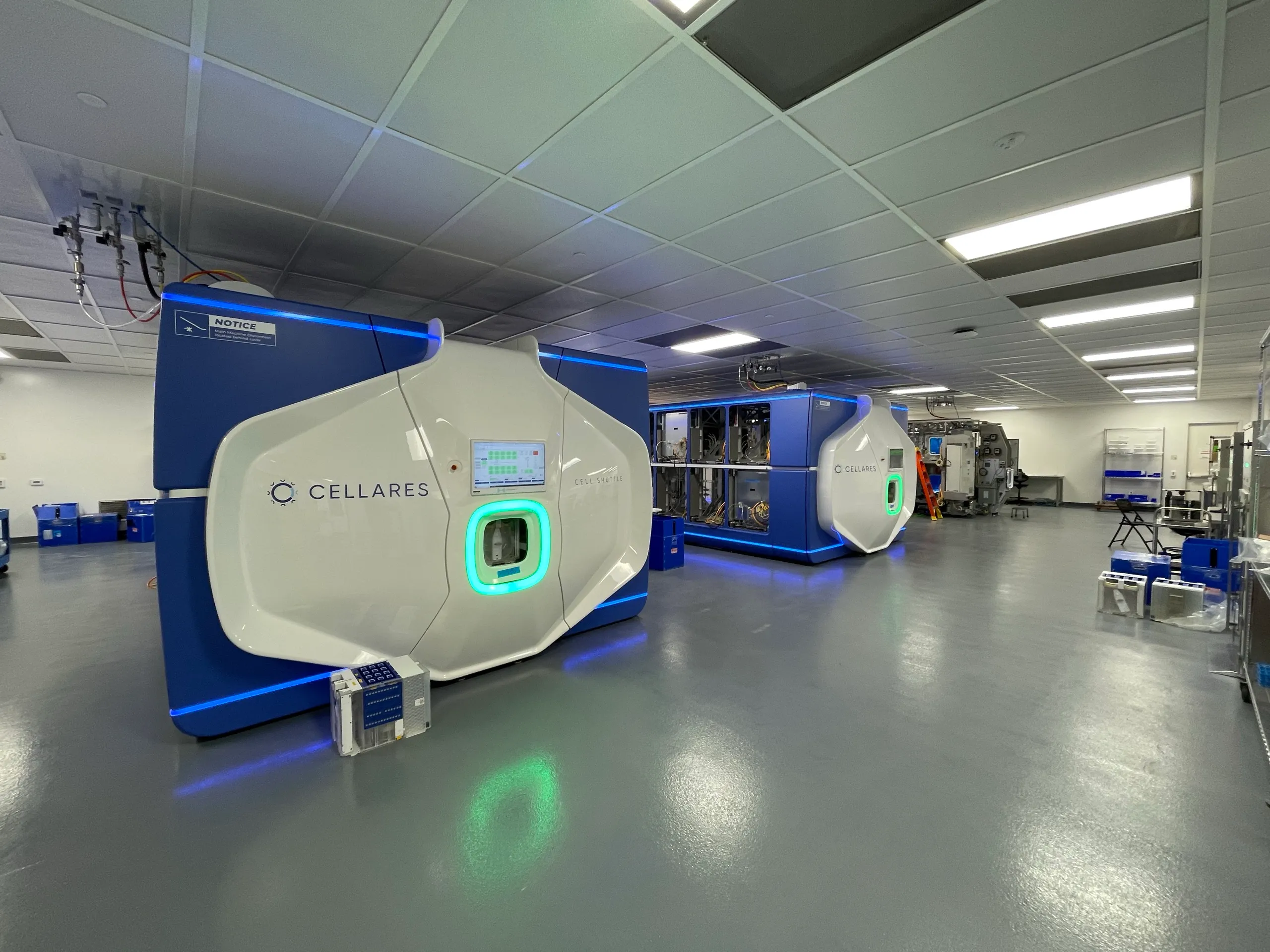 Three blue and white Cell Shuttle units in a high-bay lab, in various stages of assembly